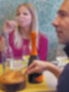 man cutting panettone with woman drinking wine